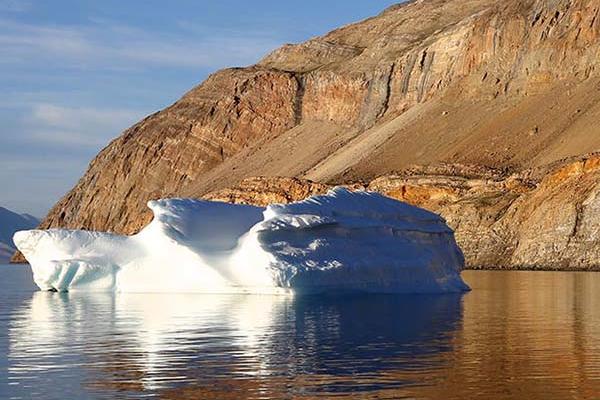 Greenland, with brown rock in background and small iceberg in the foreground.