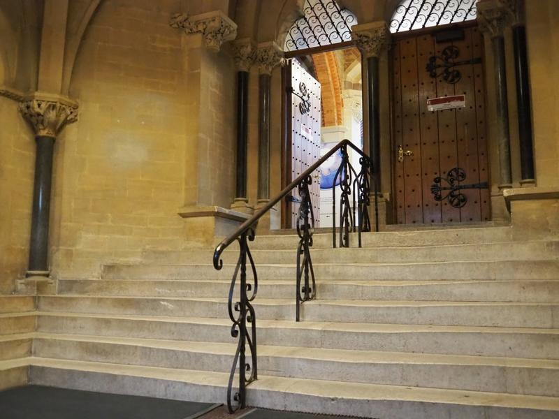 The set of stairs inside the porch with a handrail in the middle, leading up to an open door