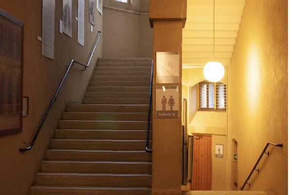 A stone staircase with handrails on both sides, seen from the Ground Floor of the Museum