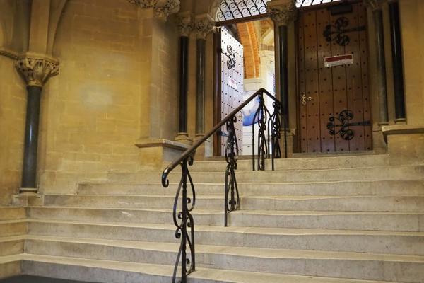 The set of stairs inside the porch with a handrail in the middle, leading up to an open door