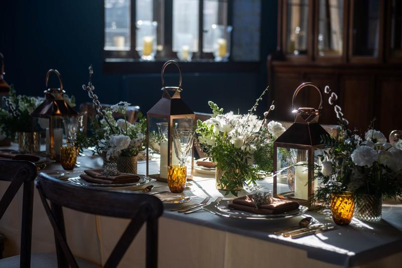 A close-up of a decorated table in the Westwood Room with lanterns and flowers